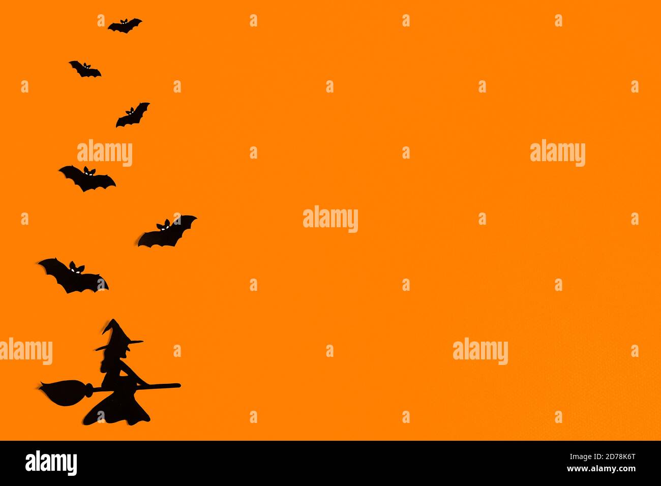 Sagome di un gregge di pipistrelli e di una strega che vola su una scopa di carta nera su sfondo arancione. Modello di saluto di Halloween con spazio per la copia Foto Stock