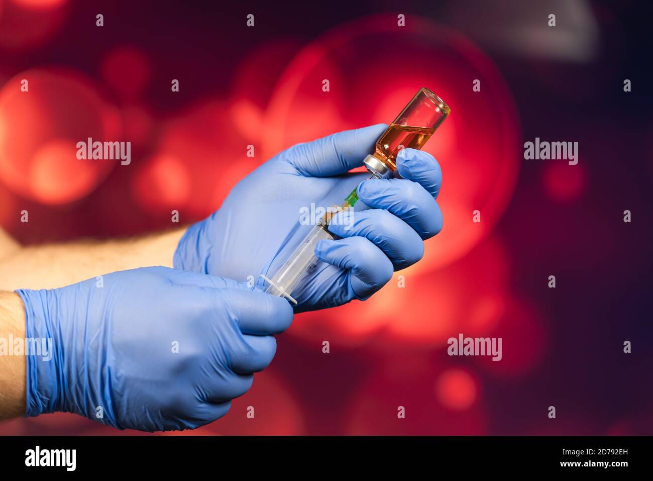 Un medico con guanti blu aspira una fiala in una siringa. Vaccino medico contro il concetto di influenza coronavirus flacone di iniezione per vetro medico Foto Stock