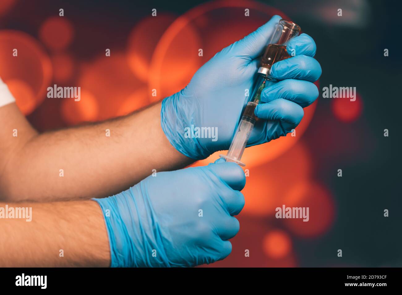 Un medico con guanti blu aspira una fiala in una siringa. Vaccino medico contro il concetto di influenza coronavirus flacone di iniezione per vetro medico Foto Stock