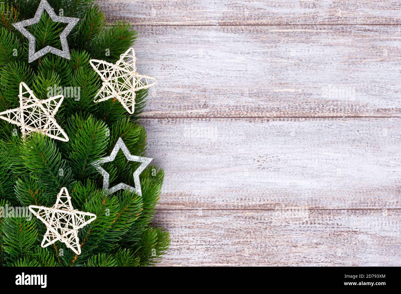 Mock up, rattan e stelle d'argento sui rami dell'albero di Natale su uno sfondo di legno Foto Stock