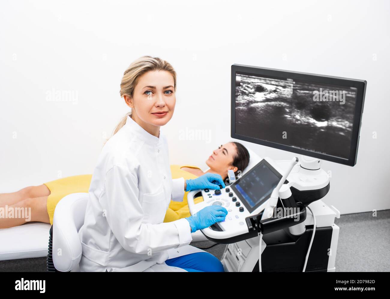 Ritratto di donna ecografo medico durante la procedura di ecografia per a. giovane paziente femminile in una clinica moderna Foto Stock