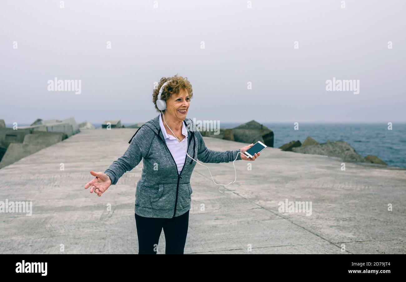 Senior donna con le cuffie e lo smartphone Foto Stock