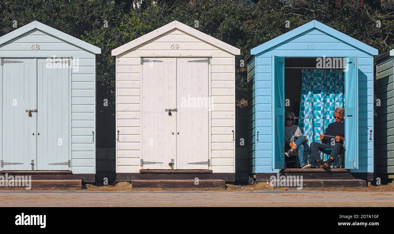 Uomo e Donna Coppia di lettura seduta in un rifugio Su Avon Beach Christchurch UK Foto Stock
