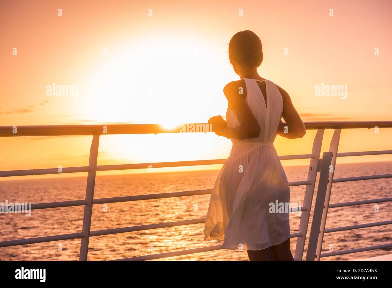 Crociera nave vacanza donna viaggio guardando il tramonto in mare vista oceano. Elegante donna in abito bianco rilassante sul balcone della terrazza, destinazione di vacanza di lusso. Foto Stock