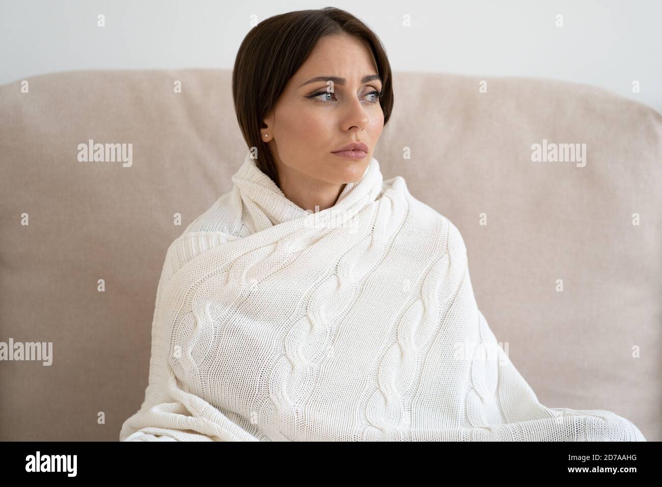 Infelice donna depressa che guarda via, siediti sul divano a casa, avvolto con plaid, pensando meditare, si sente apatia e indifferenza a tutto, ha m Foto Stock