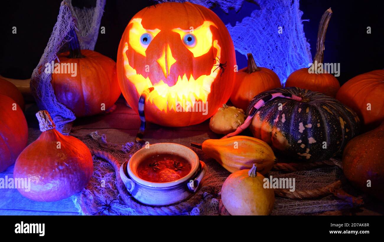 Halloween zucca Jack o lanterna e pozione di cottura in un calderone di strega. Halloween party decorazione su uno sfondo spooky. Zucca intagliata perfetta Foto Stock