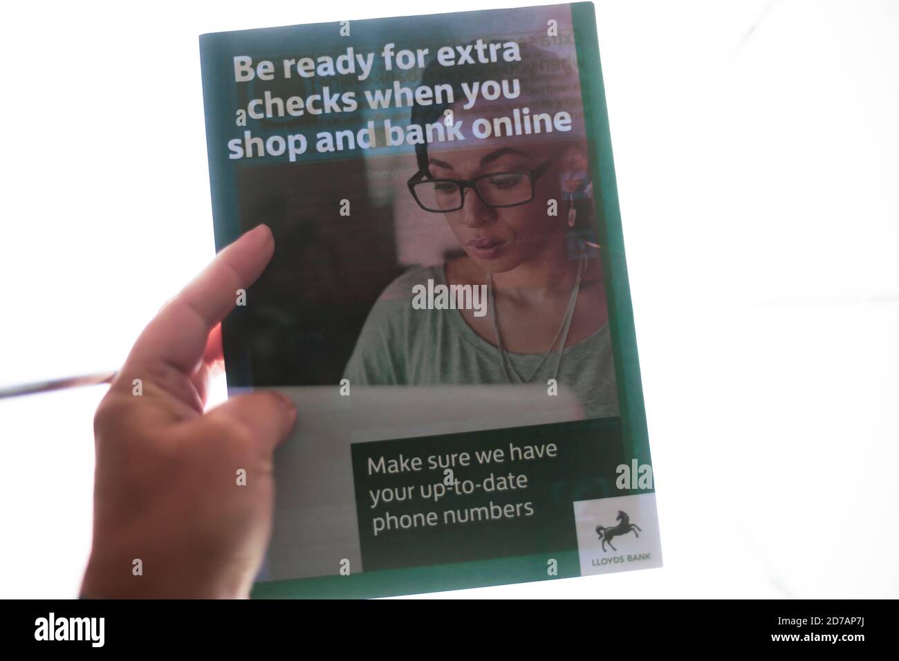 Finanza & Banking /Security Concept - primo piano di una persona Tenere a mano una guida Lloyds Bank su assegni extra in online banking & shopping Foto Stock