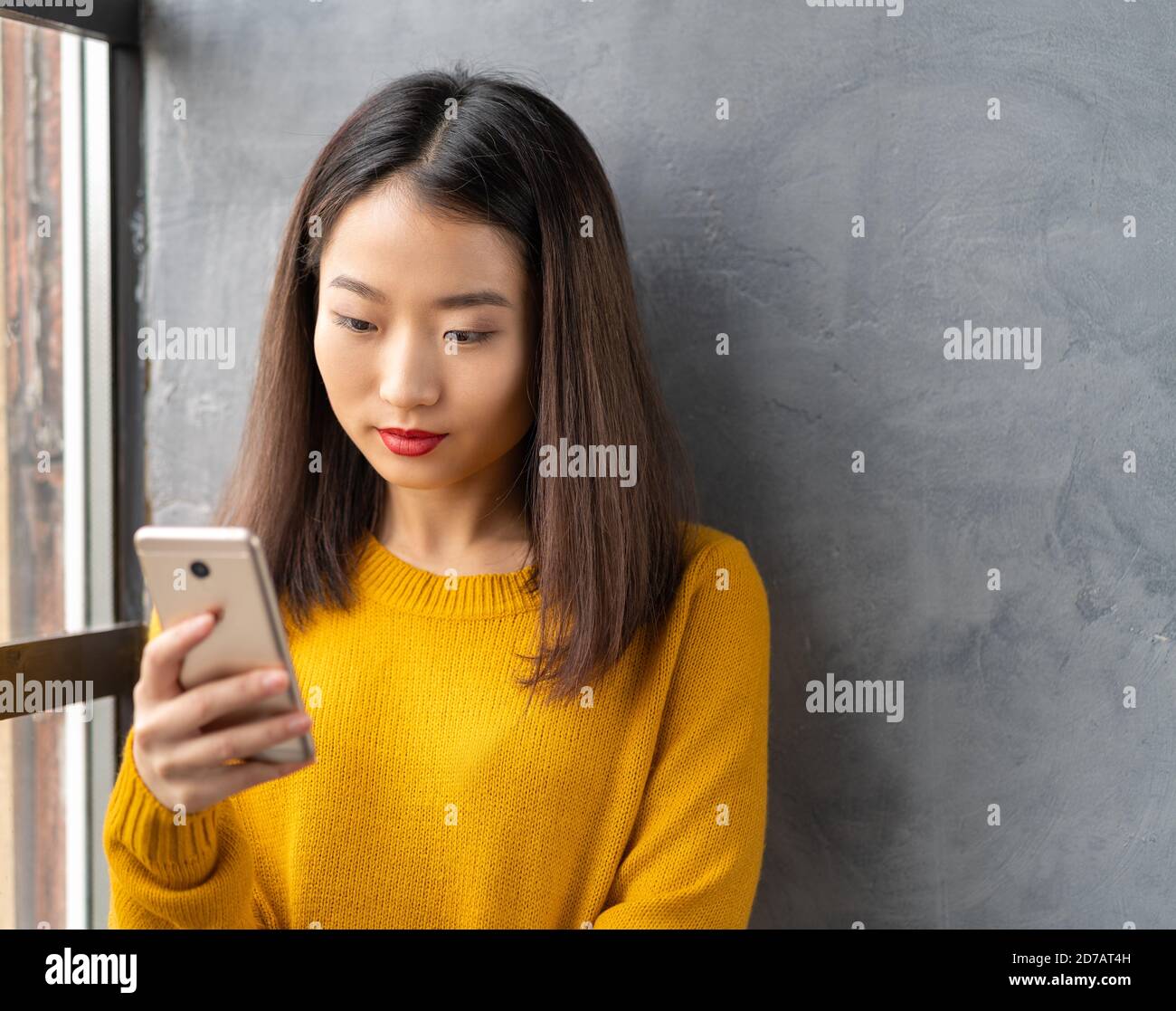 Serio, pensieroso bella giovane donna asiatica guardando il telefono cellulare, leggere i messaggi Foto Stock