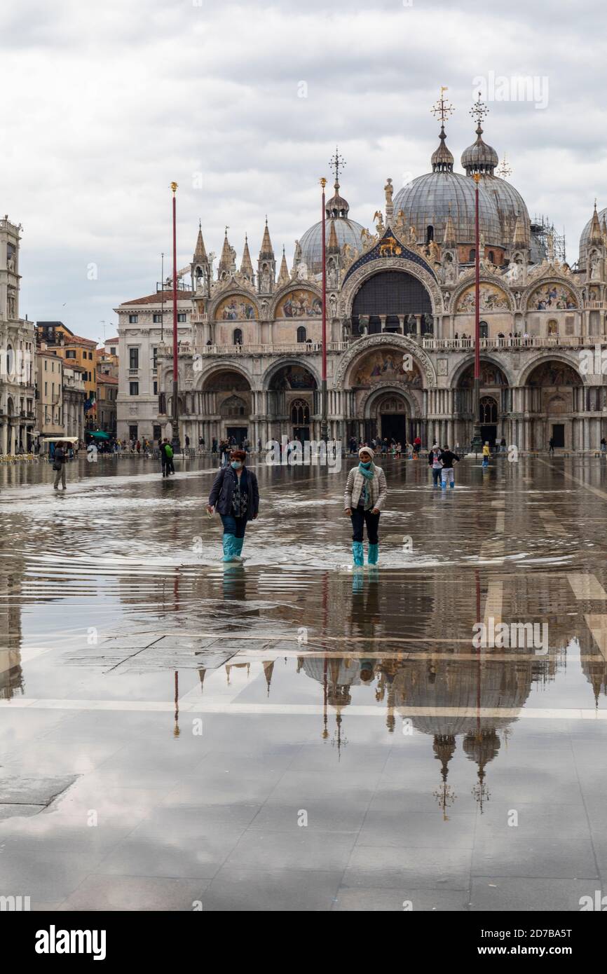 Acque alte - acqua alta causa inondazioni in Piazza San Marco. I turisti che percorre l'acqua in wellingtons. Basilica di San Marco Piazza San Marco, Venezia Foto Stock