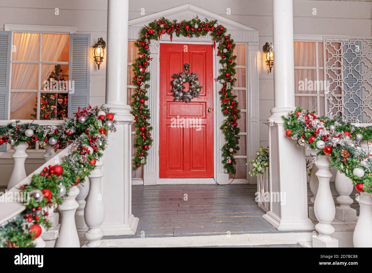 Idea di decorazione del portico di natale. ingresso di casa con porta rossa  decorata per le vacanze.