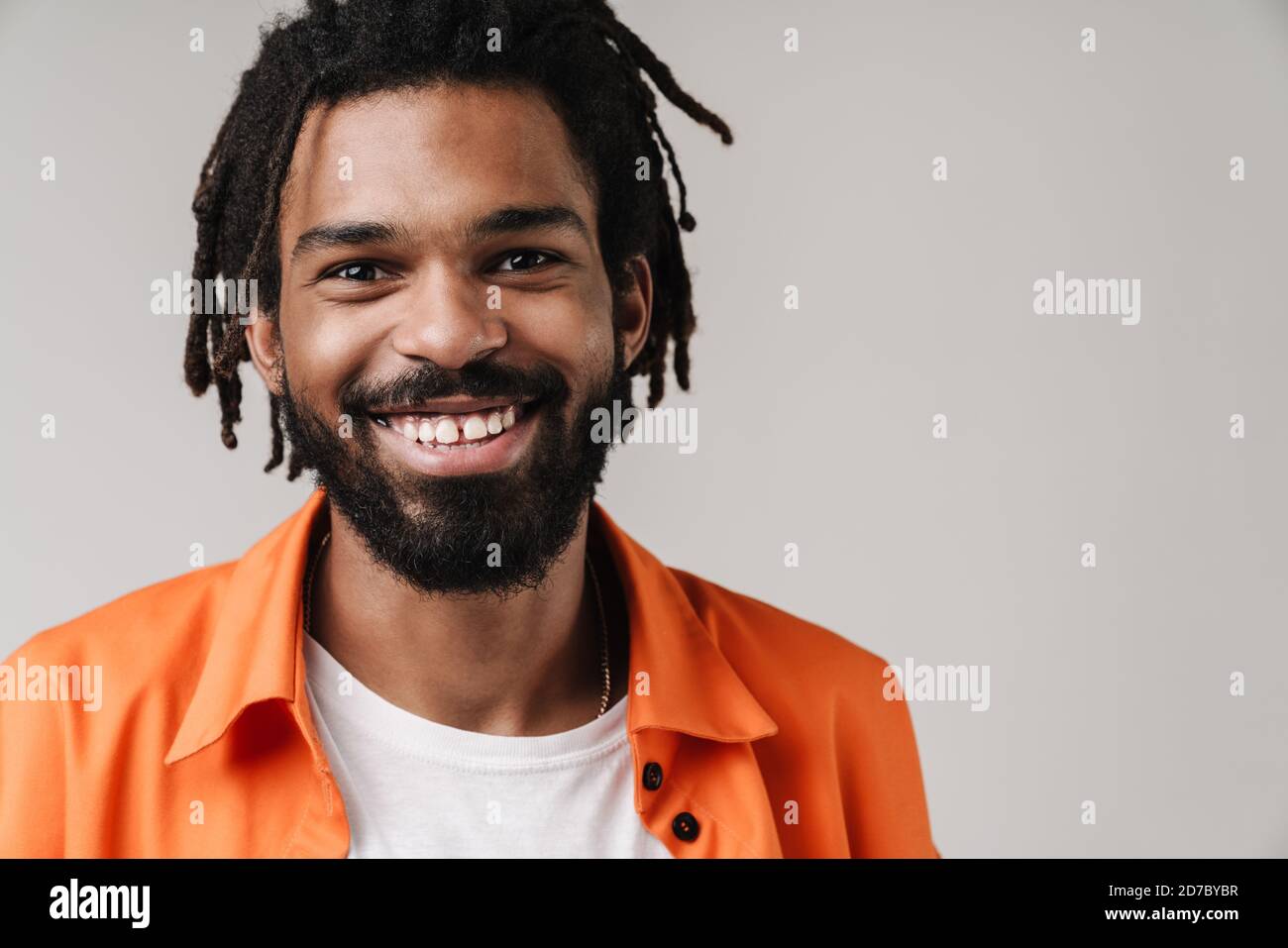 Immagine di un allegro e felice ragazzo africano che si posa isolato sopra sfondo grigio della parete Foto Stock