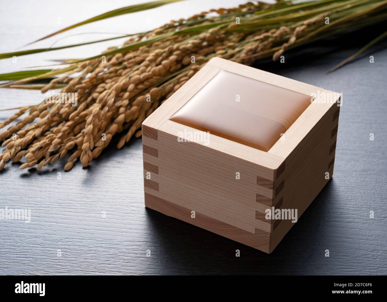 Sake è versato sullo sfondo nero. Orecchie di riso sullo sfondo. Foto Stock