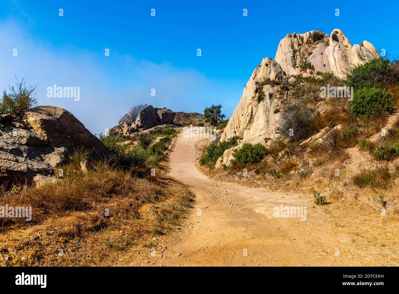 Strada sterrata che si snoda attraverso la montagna con fresche formazioni rocciose Foto Stock