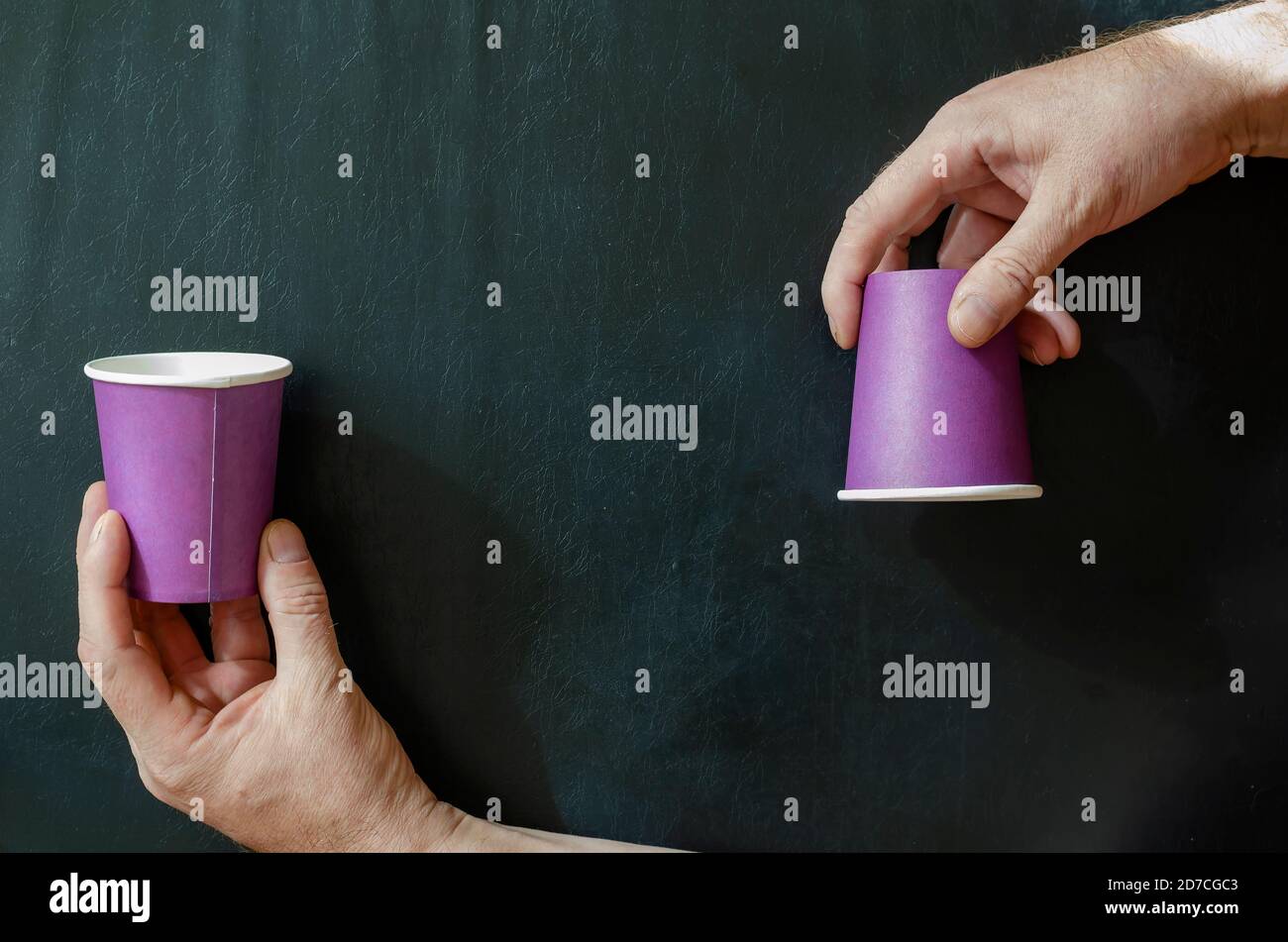 Sfondo creativo con tazze di carta per bevande calde e una mano dell'uomo. Bicchieri a mano e lilla per il caffè su sfondo nero. Vista dall'alto ad angolo. Foto Stock Sfondo creativo con tazze di carta per bevande calde e una mano dell'uomo. Bicchieri a mano e lilla per il caffè su sfondo nero. Vista dall'alto ad angolo. Foto Stock