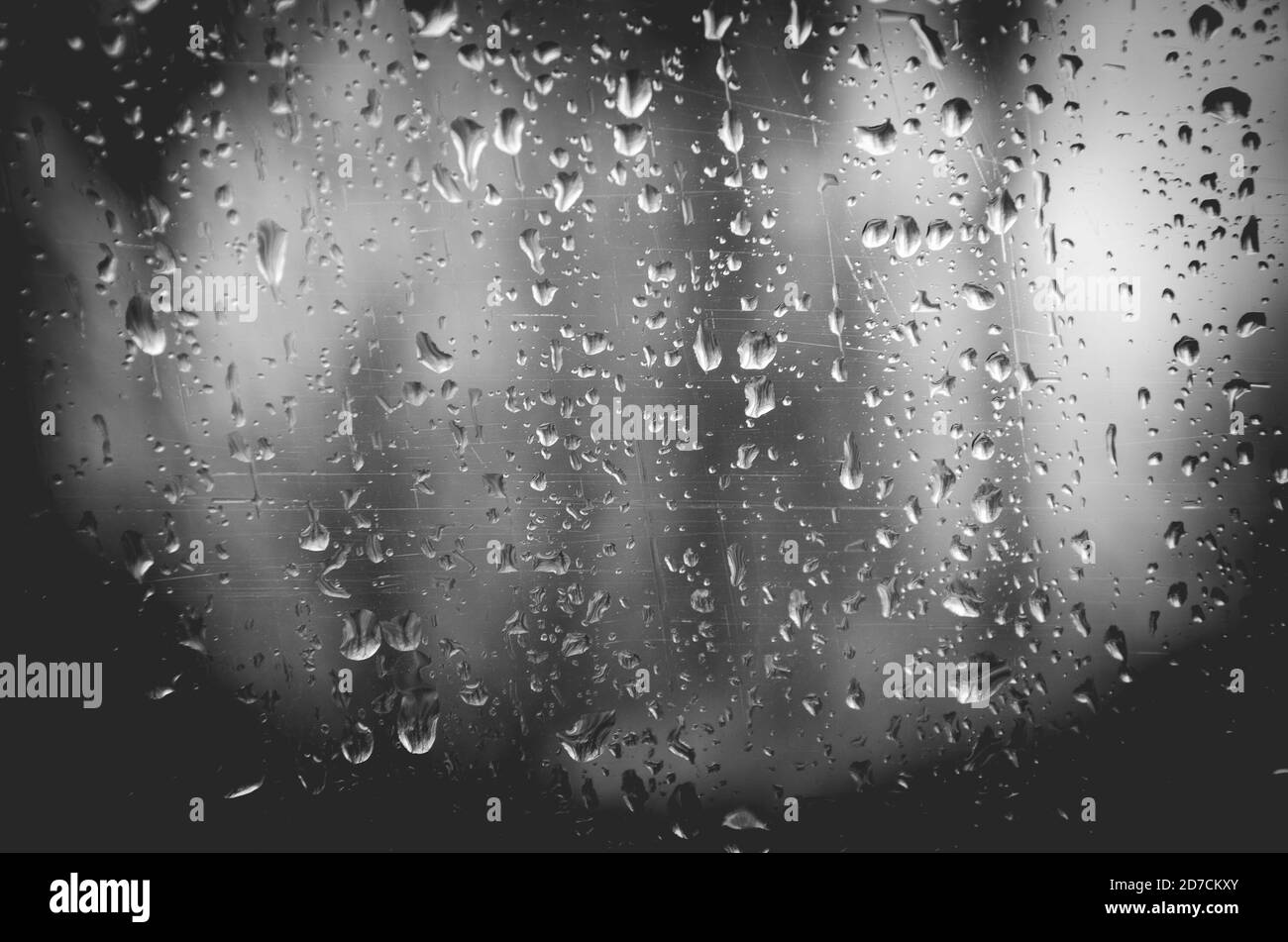 Astratto natura sfondo bianco e nero di gocce d'acqua su vetro della finestra graffiato. Foto Stock