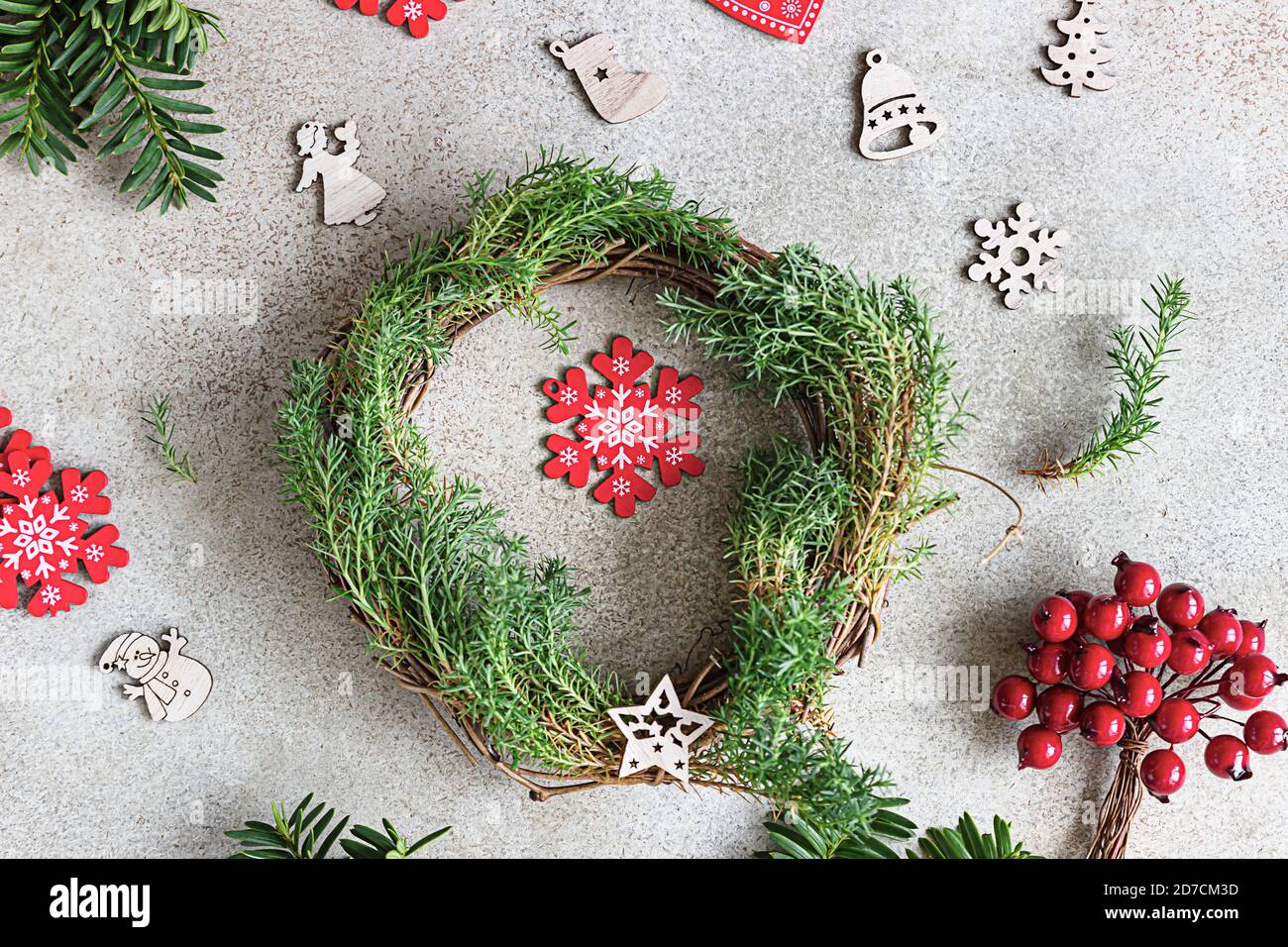 Vista dall'alto della tradizionale corona natalizia con frutti di bosco decorativi e giocattoli natalizi in legno. Festa di Natale e di inverno concetto di celebrazione. Foto Stock