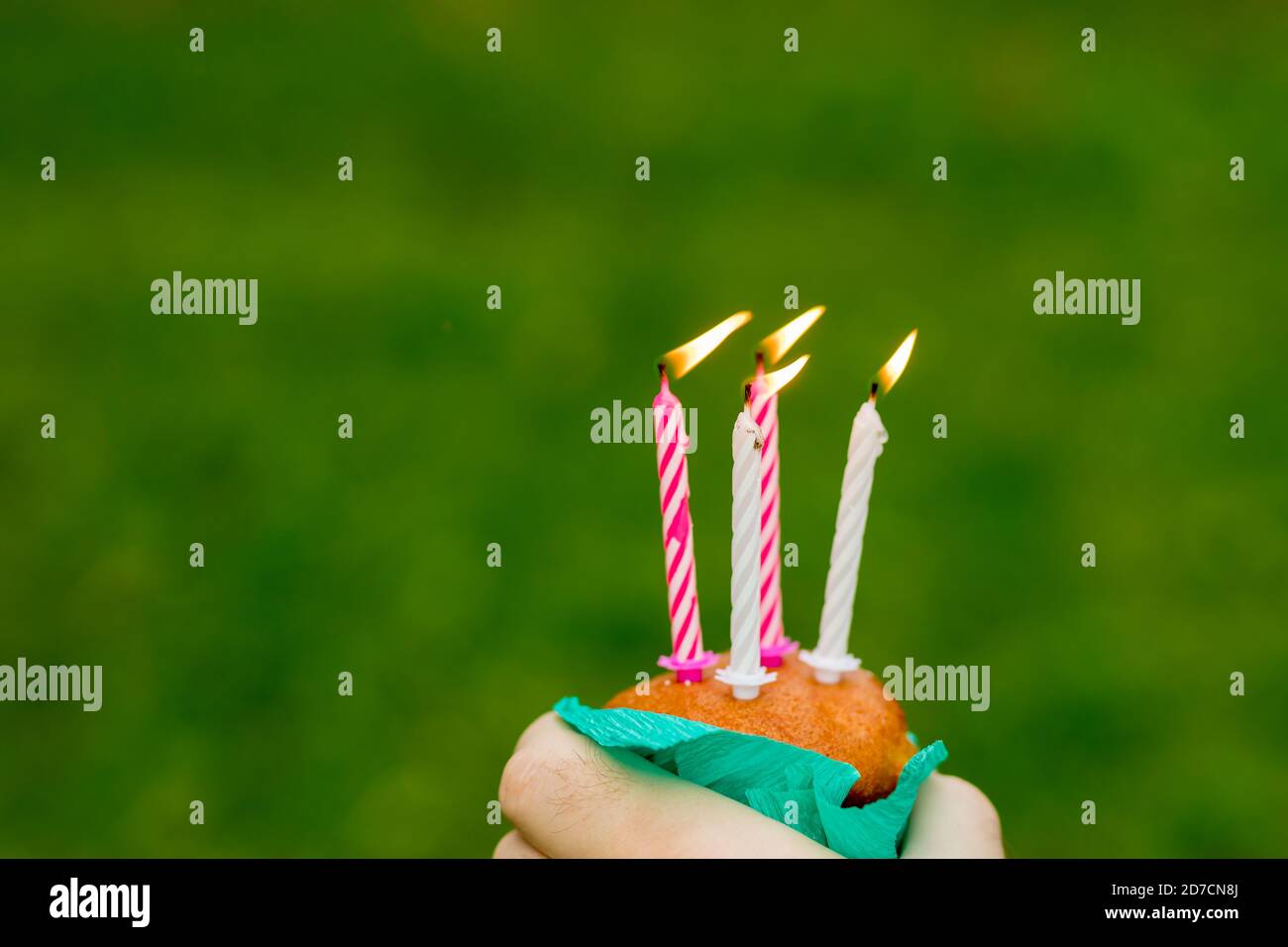 Mini cupcake con quattro candele per quattro anni di anniversario isolato su sfondo verde.Anniversary Celebration.Congratulazioni card. Candele che bruciano Foto Stock