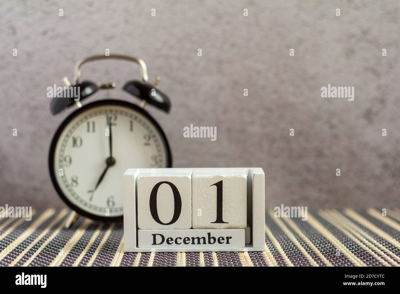 1 dicembre su un calendario di legno accanto a una sveglia su un tavolo scuro. Primo giorno di winter.Hello dicembre, Ciao inverno. Foto Stock