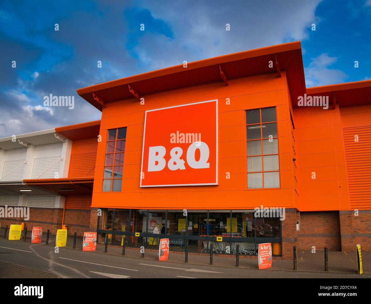 La facciata e il logo del marchio di una filiale del negozio di fai da te britannico B&Q, in un parco al dettaglio locale a Wirral, Regno Unito, in un pomeriggio di sole Foto Stock