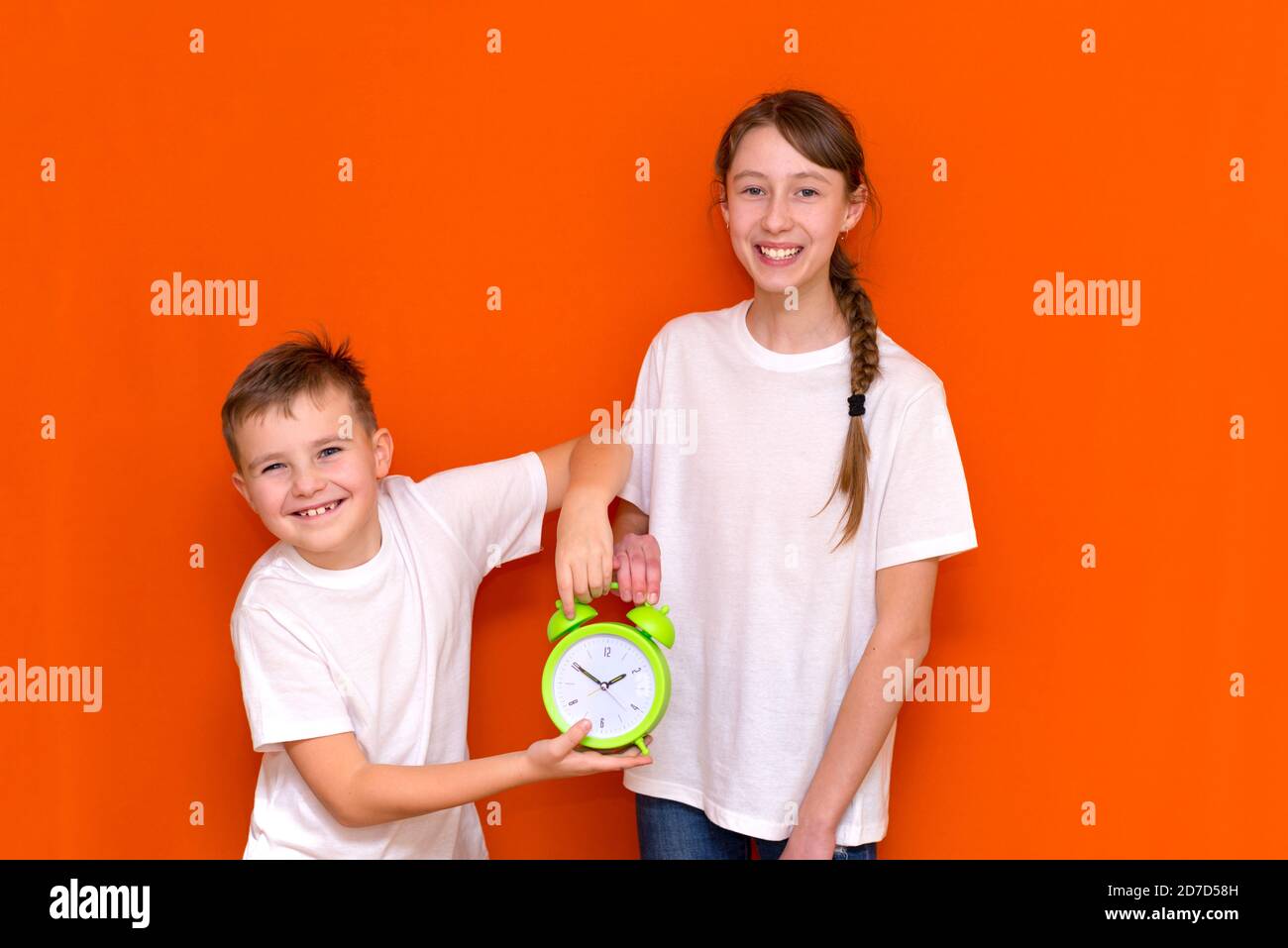 Ridendo giovani caucasici due amici ragazzo e ragazza in bianco vuoto vuoto design t-shirt in posa sulla parete arancione studio. Foto Stock