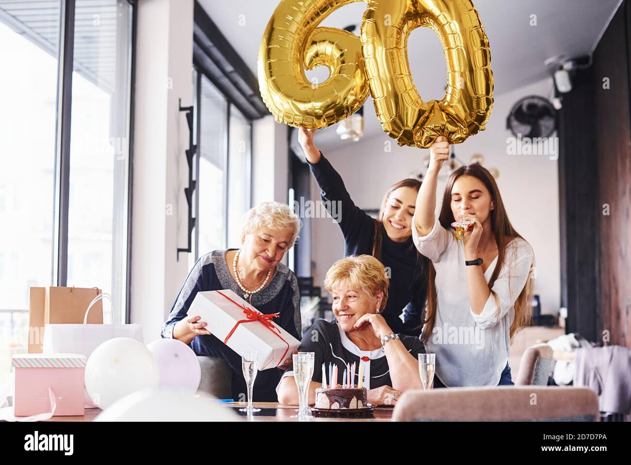 Palloncini con numero 60. Donna anziana con la famiglia e gli amici che  festeggiano un compleanno all'interno Foto stock - Alamy