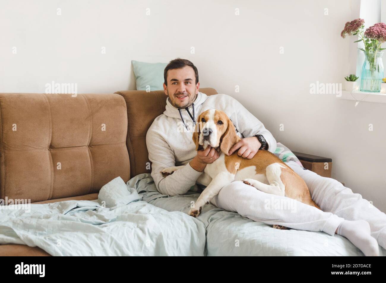 un uomo sta sdraiato sul divano e lo stropone amato cane Foto Stock