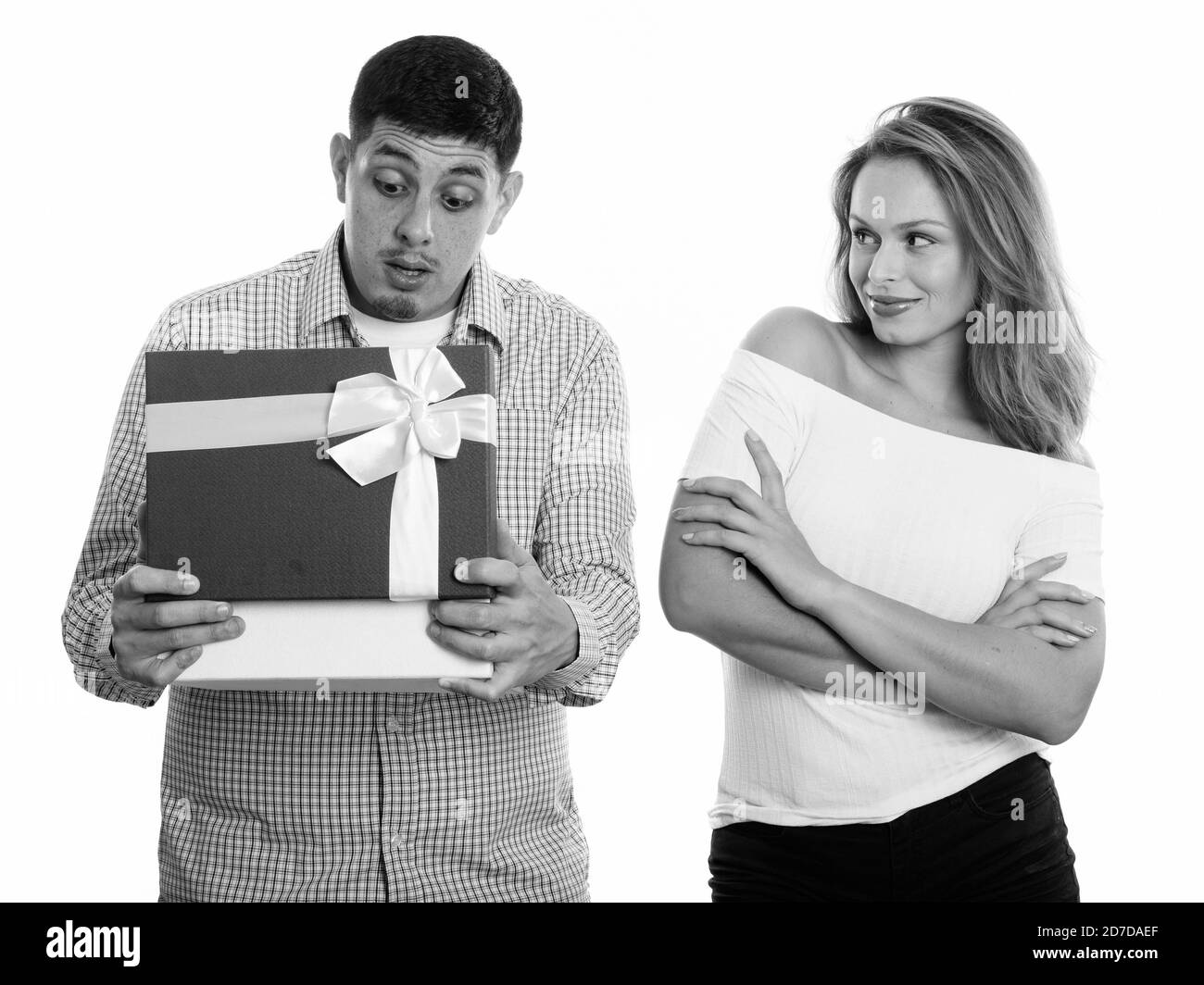 Studio shot di coppia giovane in amore con l'uomo apertura scatola regalo cercando sorpreso Foto Stock
