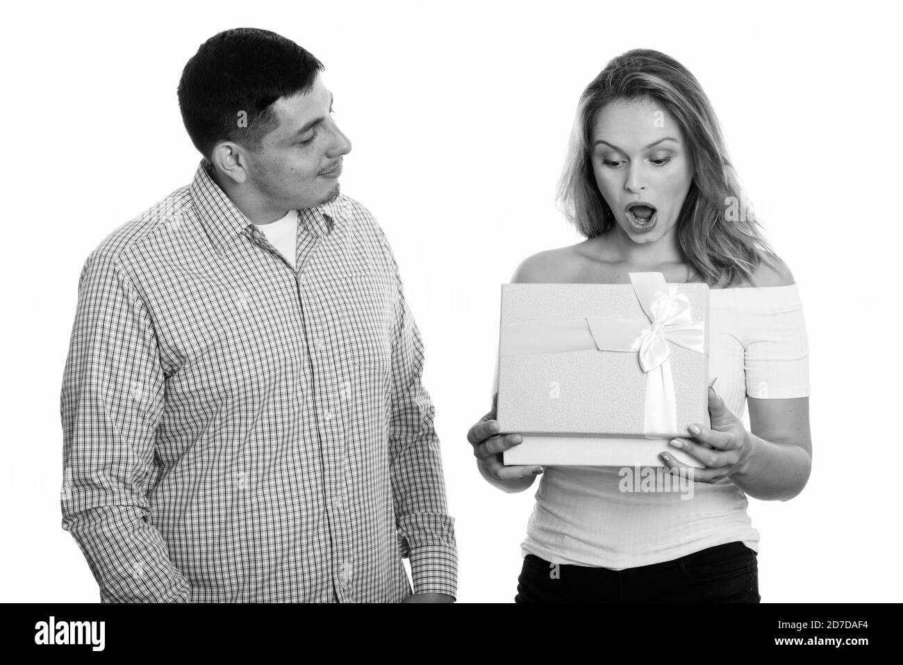 Studio shot di coppia giovane in amore con la donna apertura scatola regalo cercando sorpreso Foto Stock