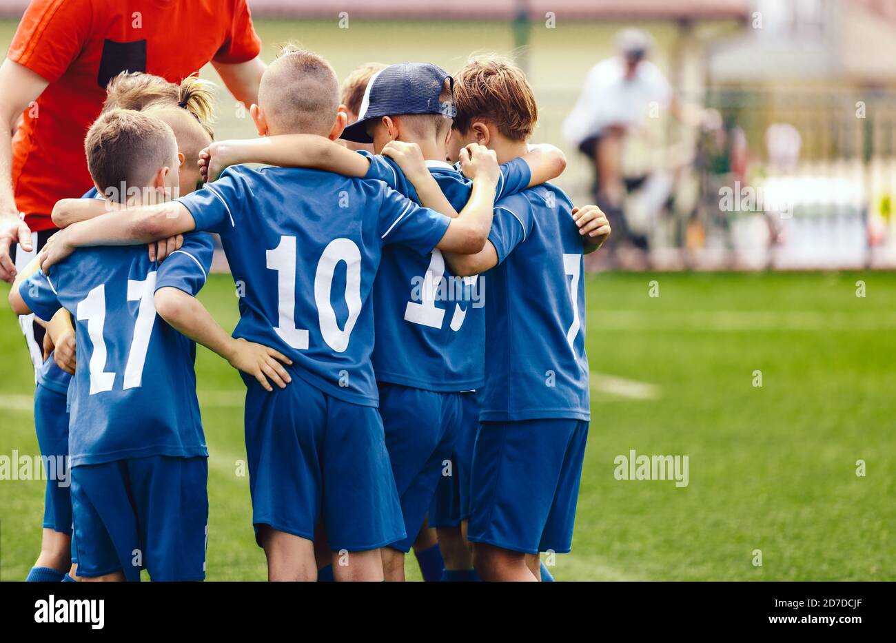 Bambini in scuola elementare squadra sportiva con allenatore. Ragazzi in  divise da calcio blu con numeri bianchi sul retro. Allenatore motivare i  bambini giocatori di calcio essere Foto stock - Alamy