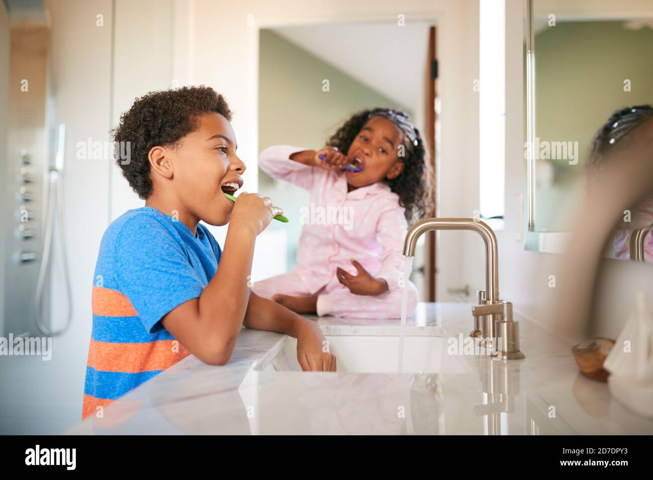 Due bambini che spazzolano i denti in bagno a casa Foto Stock