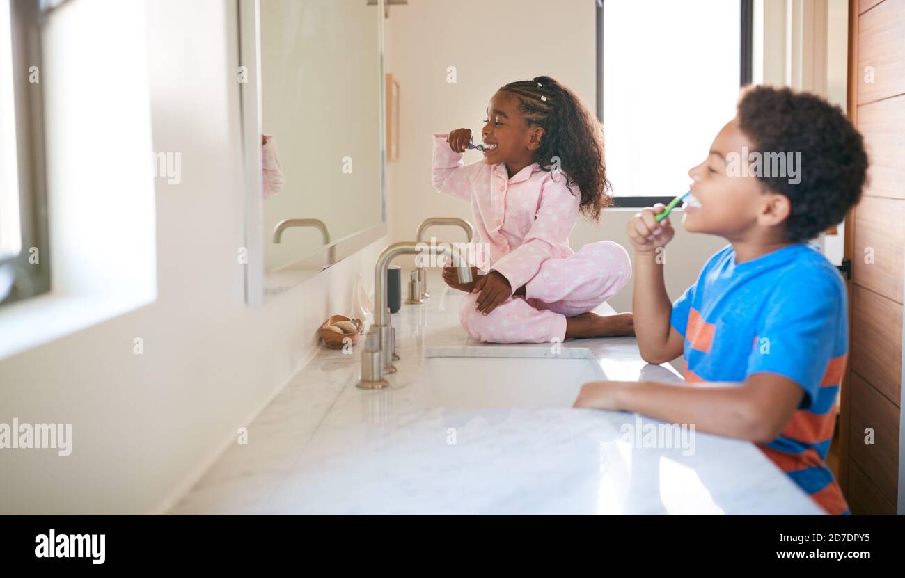 Due bambini che spazzolano i denti in bagno a casa Foto Stock