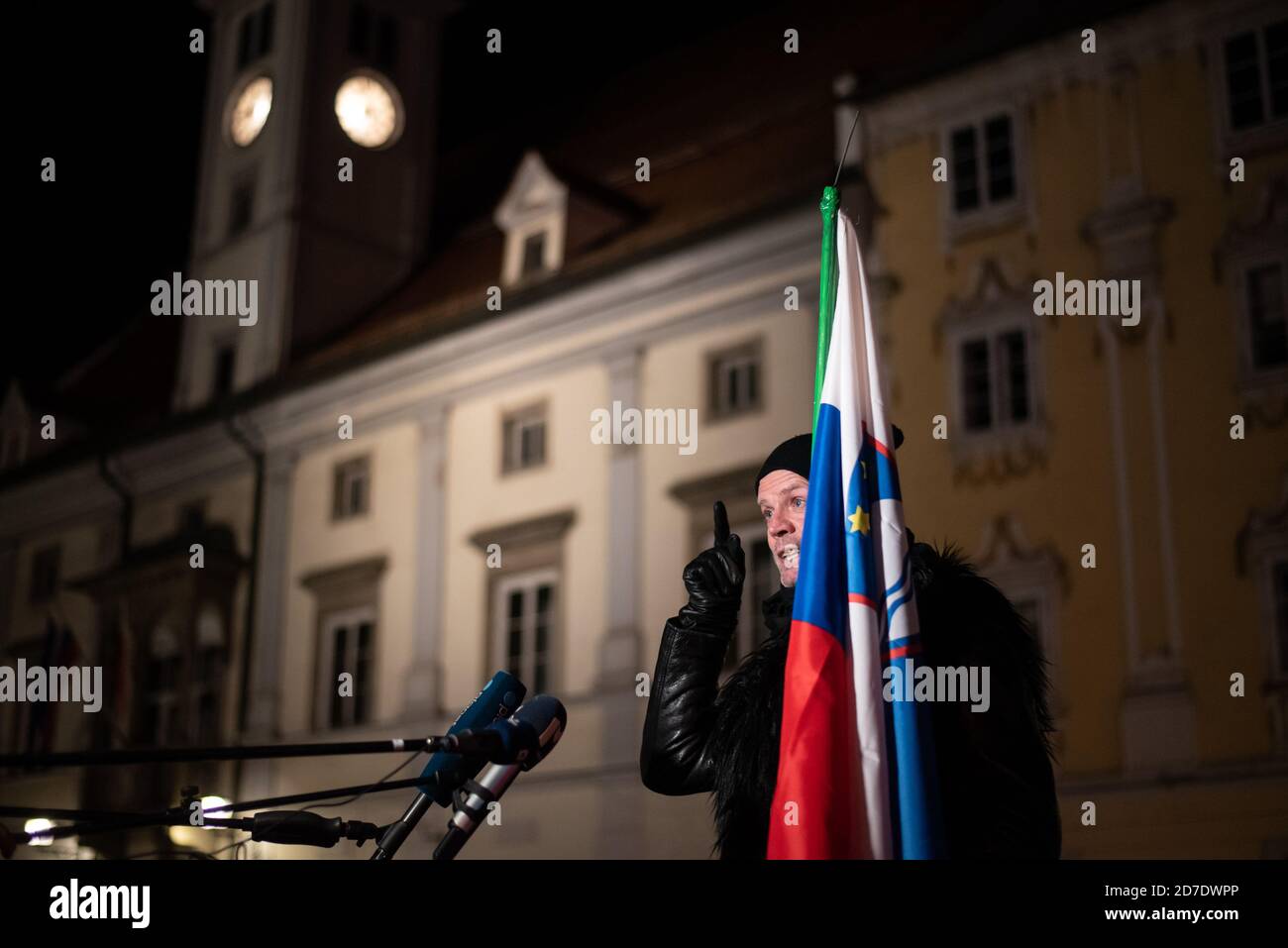 Un manifestante contro l'applicazione del coprifuoco notturno e le restrizioni di blocco parla di premere mentre si tiene la bandiera slovena oltre le ore notturne del coprifuoco. La Slovenia ha ridonato un'epidemia e ha adottato misure rigorose per prevenire la diffusione del coronavirus (Covid-19). Per la prima volta è stato applicato un coprifuoco dalle 21:00 alle 6:00. Foto Stock