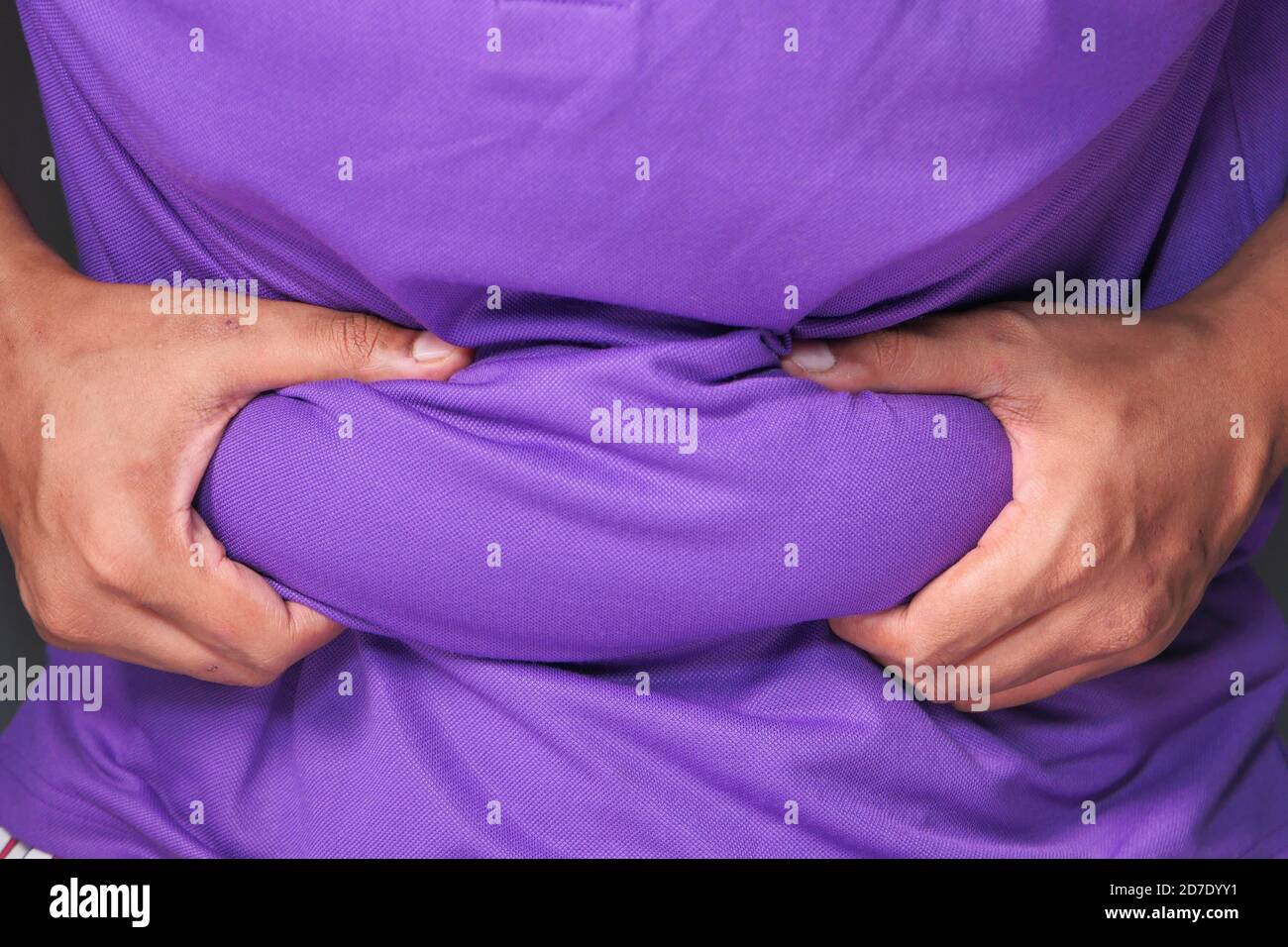 mano dell'uomo che tiene eccessivo grasso di pancia, concetto di sovrappeso Foto Stock