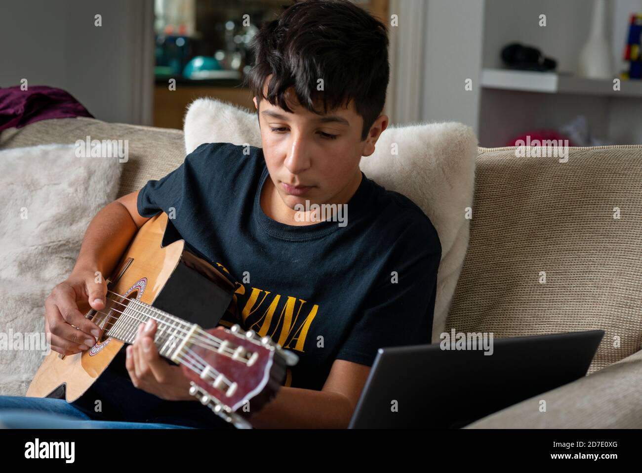 Teenage boy, 13 anni, suonando messa a fuoco selettiva per chitarra acustica Foto Stock