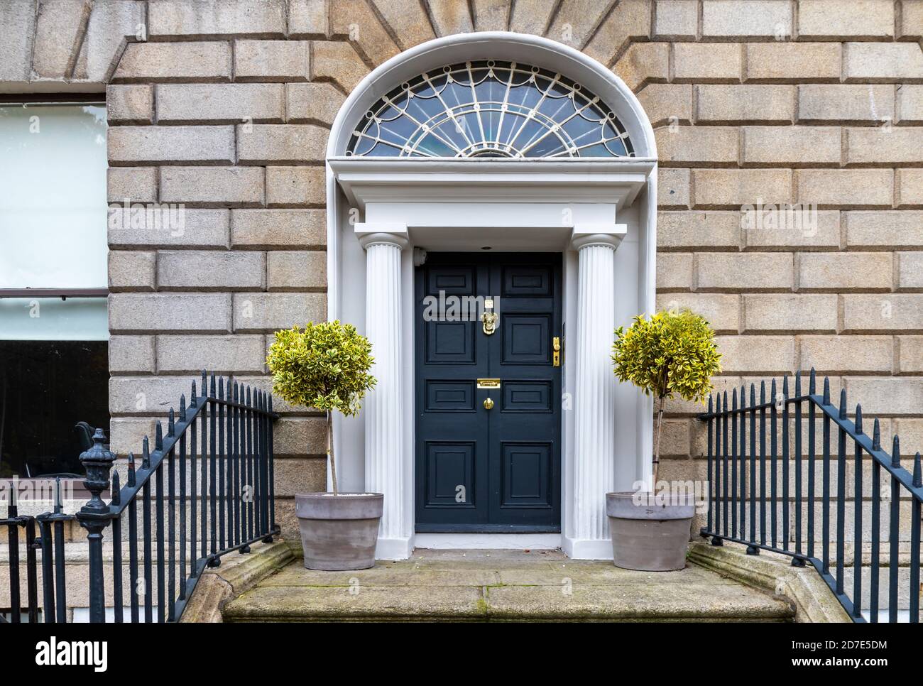 Porta nera georgiana, ingresso alla casa, con due alberi in pentole. Faro a ventaglio decorativo, ferramenta in ottone, colonne, ringhiere e gradini. Dublino, Irlanda Foto Stock