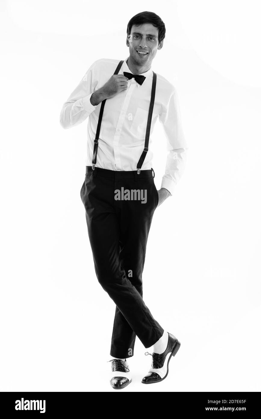 Corpo pieno colpo di giovane uomo felice sorridere mentre indossare calze autoreggenti e trattenere il filtro bow tie Foto Stock