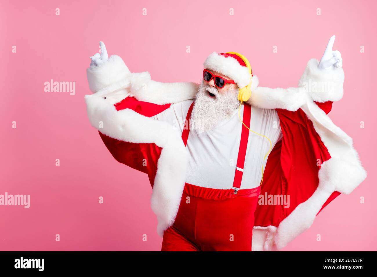 Foto pazzo funky fresca barba babbo natale godere di ascoltare stereo cuffie per musica volumetrica con un'atmosfera agile, x-mas christmas songs indossano per il nuovo anno pantaloni sospendenti Foto Stock