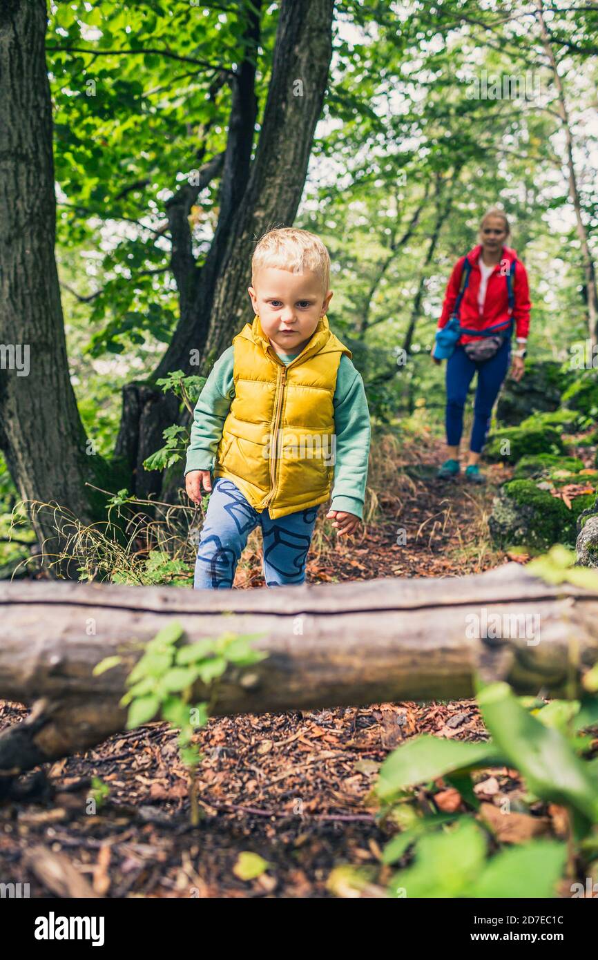 Little boy escursioni con la madre, avventura in famiglia. Piccolo bambino che cammina nella foresta rocciosa verde. Foto Stock