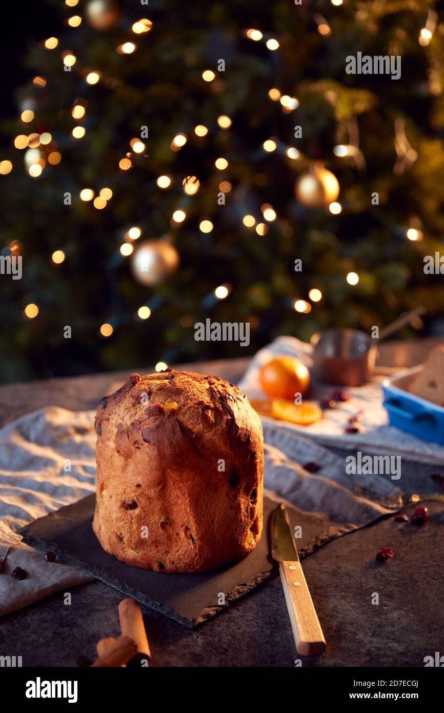 Tradizionale Panettone di Natale sul tavolo insieme per il pasto festivo con Luci ad albero in background Foto Stock