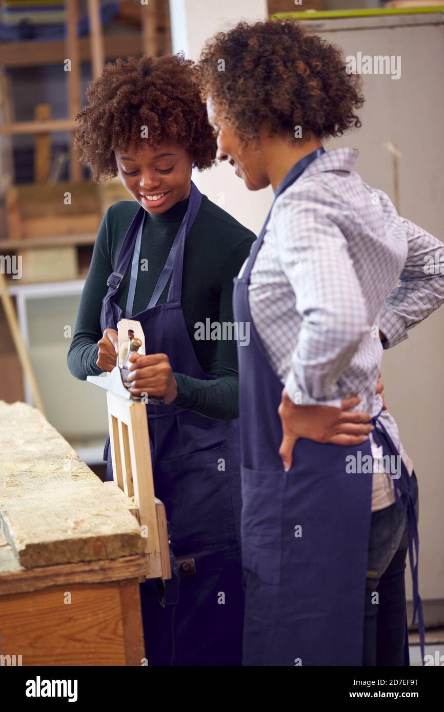 Tutor con studente di carpenteria femminile in Workshop studiando per l'apprendistato A legno di planata dell'università Foto Stock