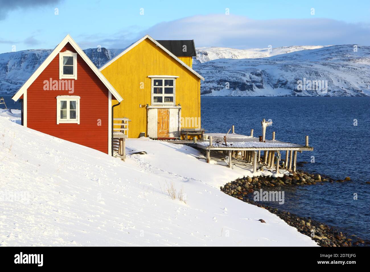 Vecchio molo di pesca nel nord della Norvegia. Una casa gialla e rossa vicino al mare in un fiordo norvegese. Penisola di Varanger nella contea di Finmark. Foto Stock