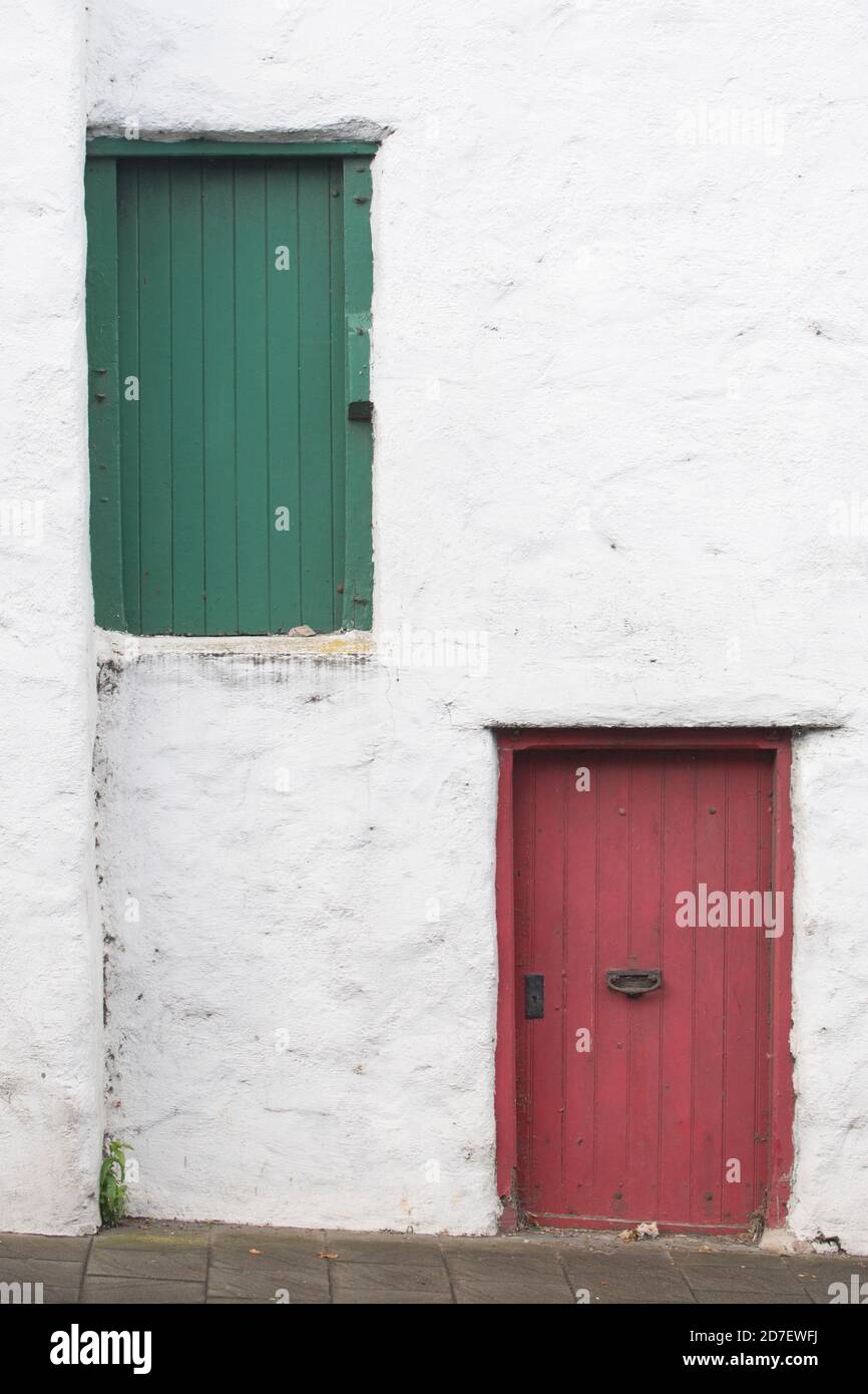 Porte verdi e rosse in un muro bianco a Bushmills, Irlanda del Nord, Regno Unito Foto Stock
