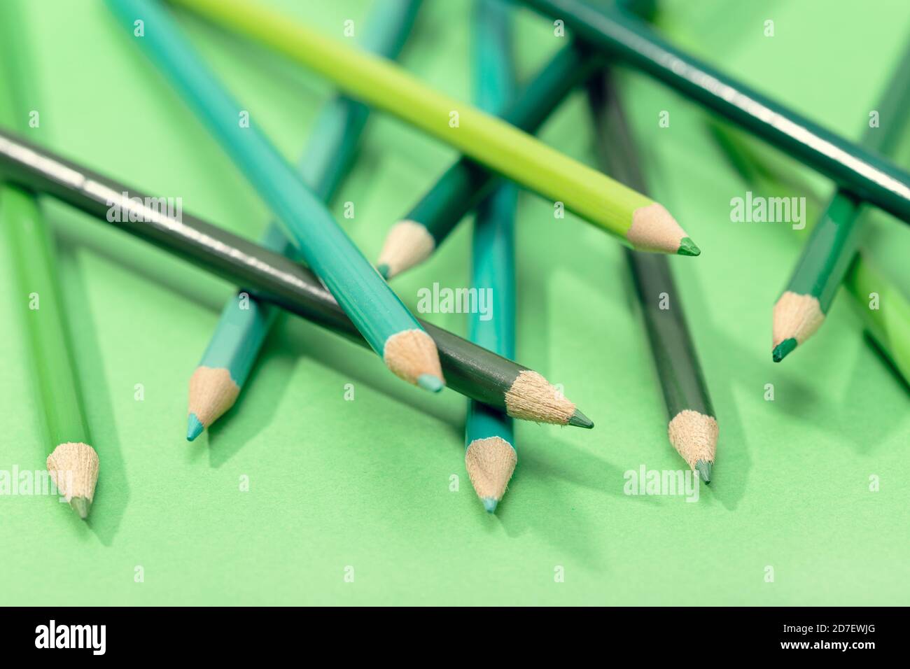 Matite miste di colore verde su tavolo verde. Formazione verde background Foto Stock