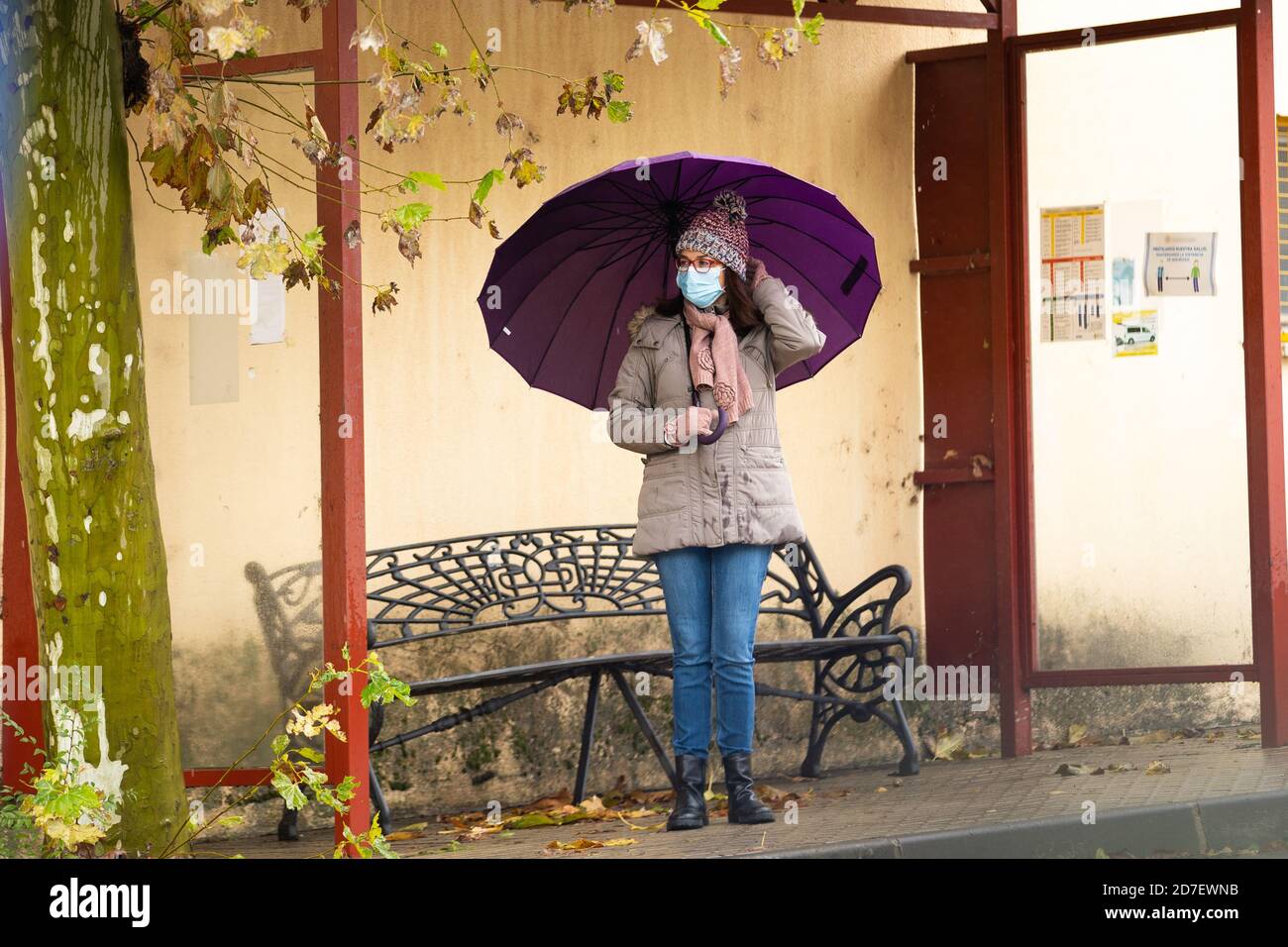 Donna con ombrello alla fermata dell'autobus Foto Stock