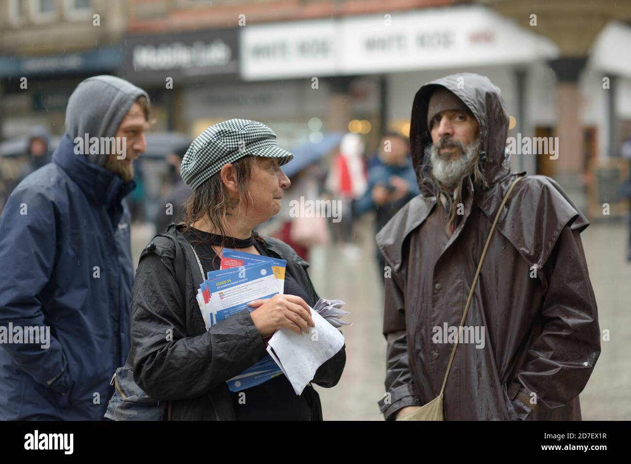 Manifestanti con volantini, alla protesta della teoria della cospirazione, sotto la pioggia. Foto Stock