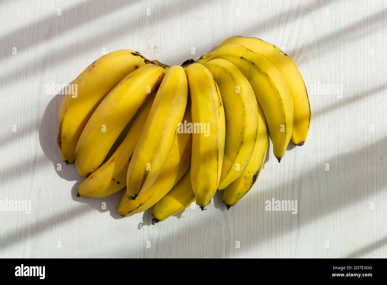 deliziose banane fresche con un bianco sfondo sole e ombra, design di sfondo in uno studio, stile di vita sano Foto Stock
