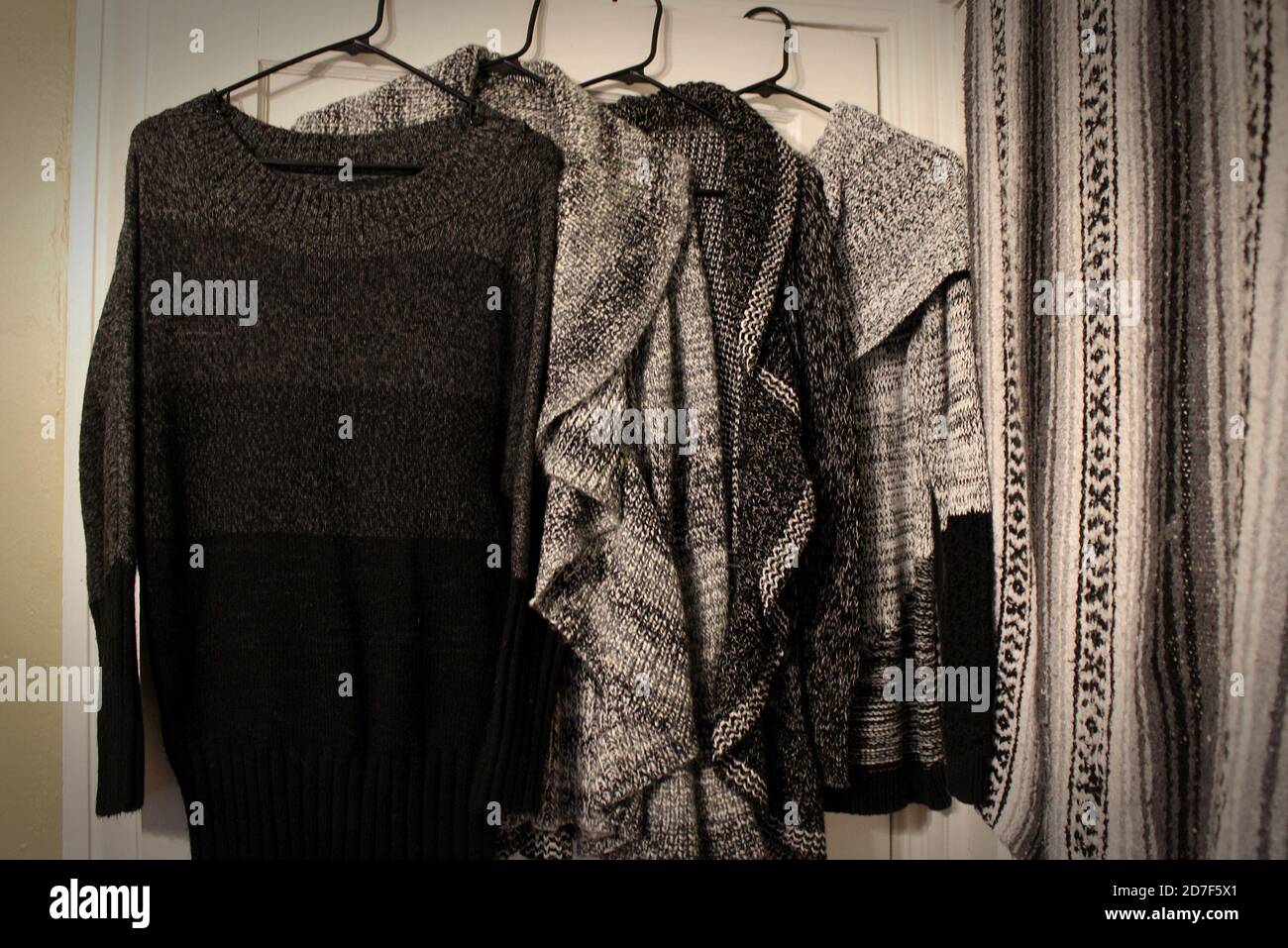 la mia selezione di pullover in maglia nera, grigia e bianca si coordina con la mia coperta di falsa tessuta Foto Stock