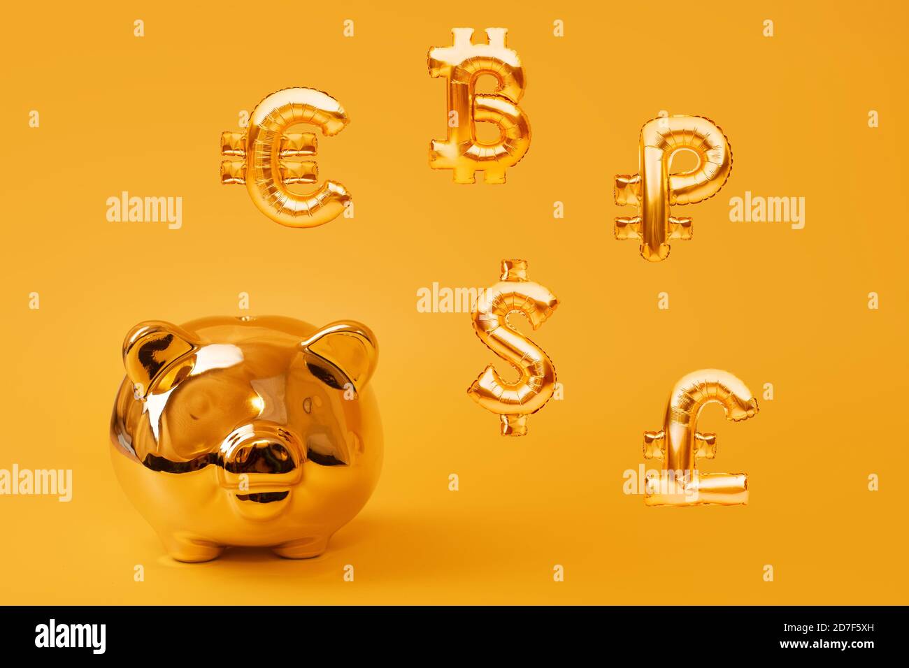 Golden piggy bank su sfondo giallo con simboli di valuta dorata fatti di palloncini gonfiabili. Investimento e concetto bancario. Risparmio di denaro Foto Stock