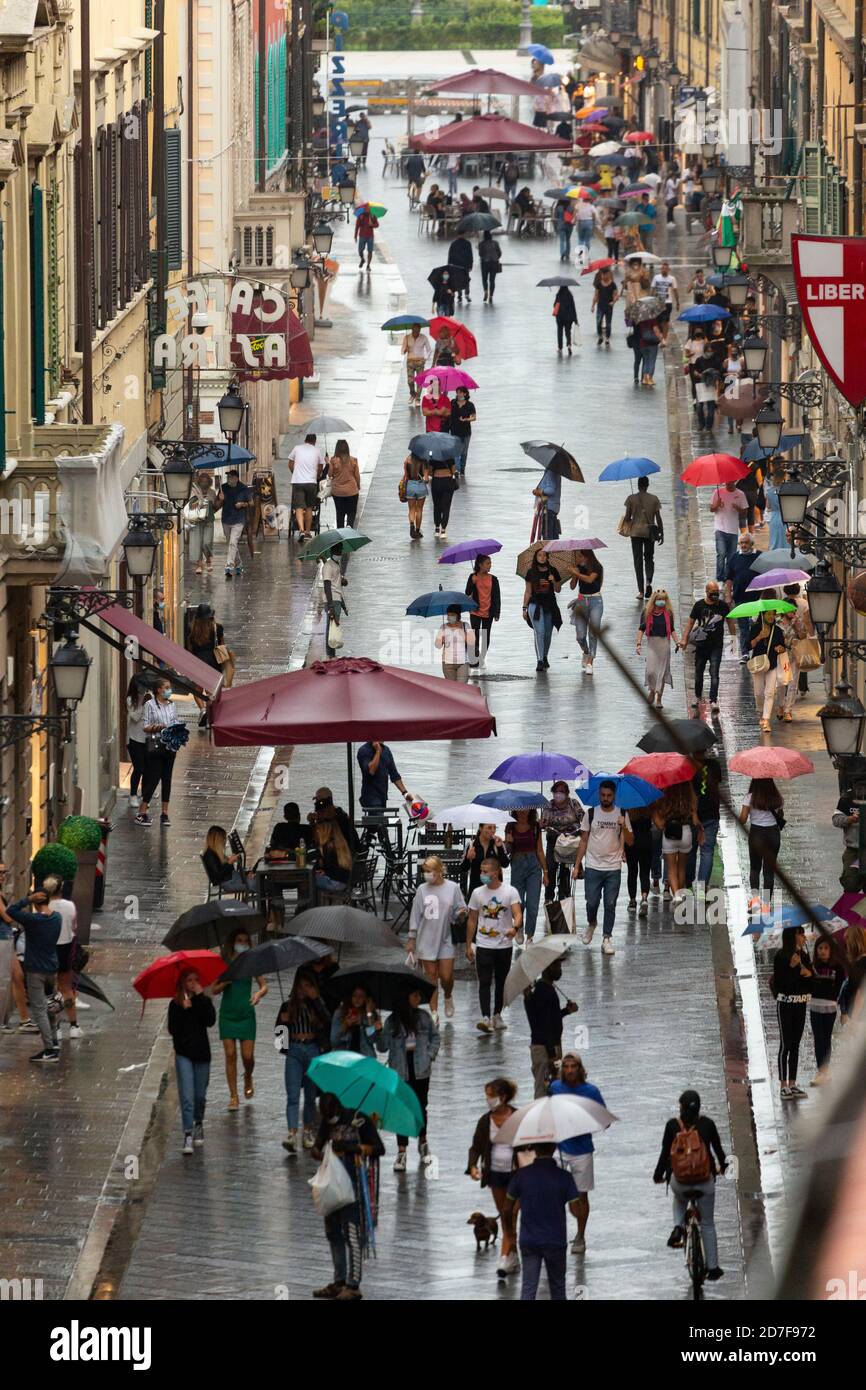 Pedoni che camminano lungo corso Italia con ombrelloni in una giornata piovosa, Pisa, Toscana, Italia Foto Stock