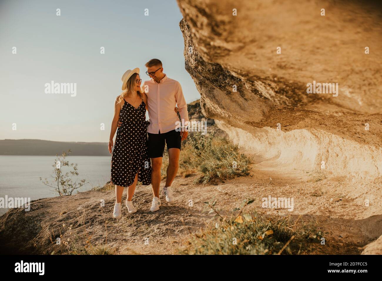l'uomo e la donna in cappello camminano lungo le rocce sopra il scogliera Foto Stock
